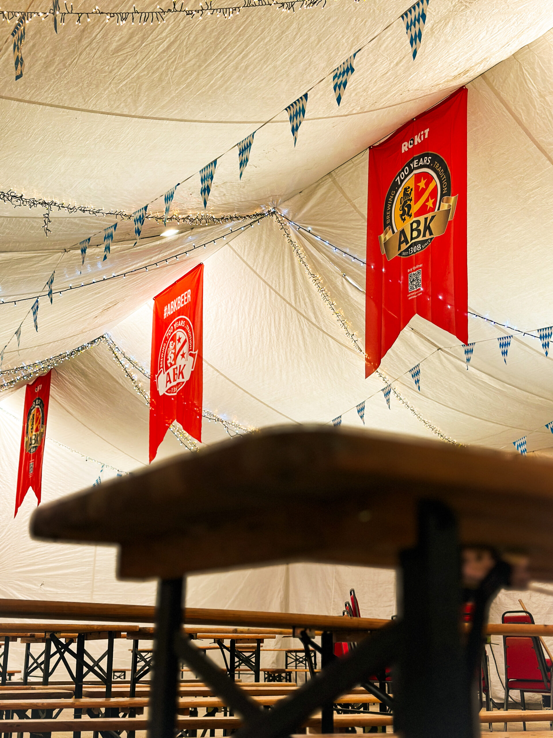 Fairy lights and Bavarian bunting strung across the marquee ceiling above the beer-hall benches